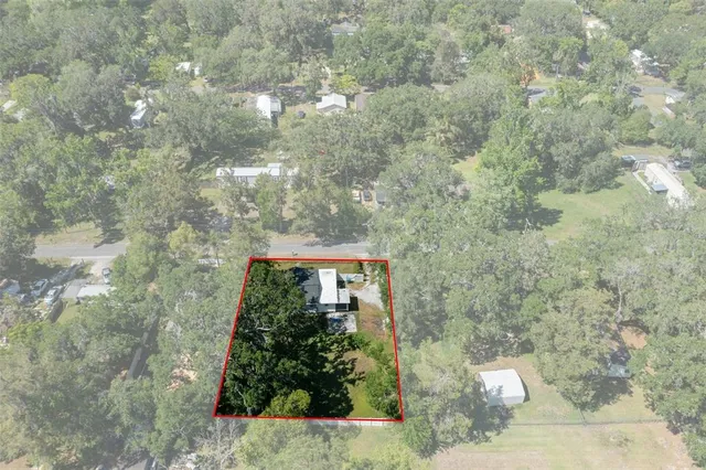 an aerial view of residential house with outdoor space and trees all around