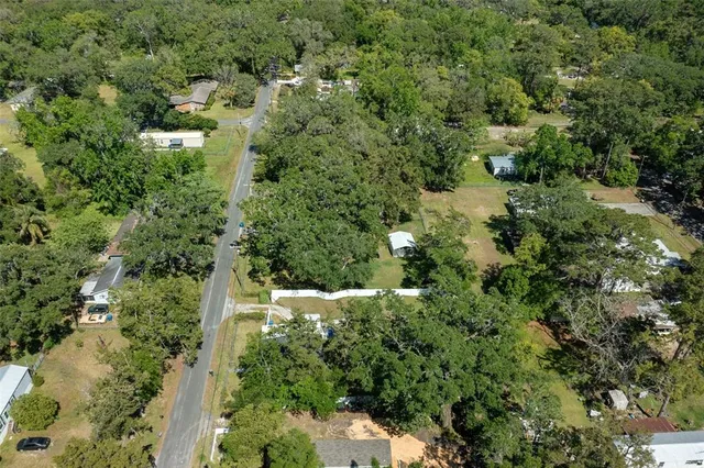 an aerial view of residential houses with outdoor space and trees