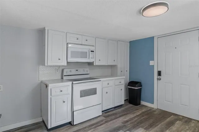 a kitchen with cabinets appliances and wooden floor