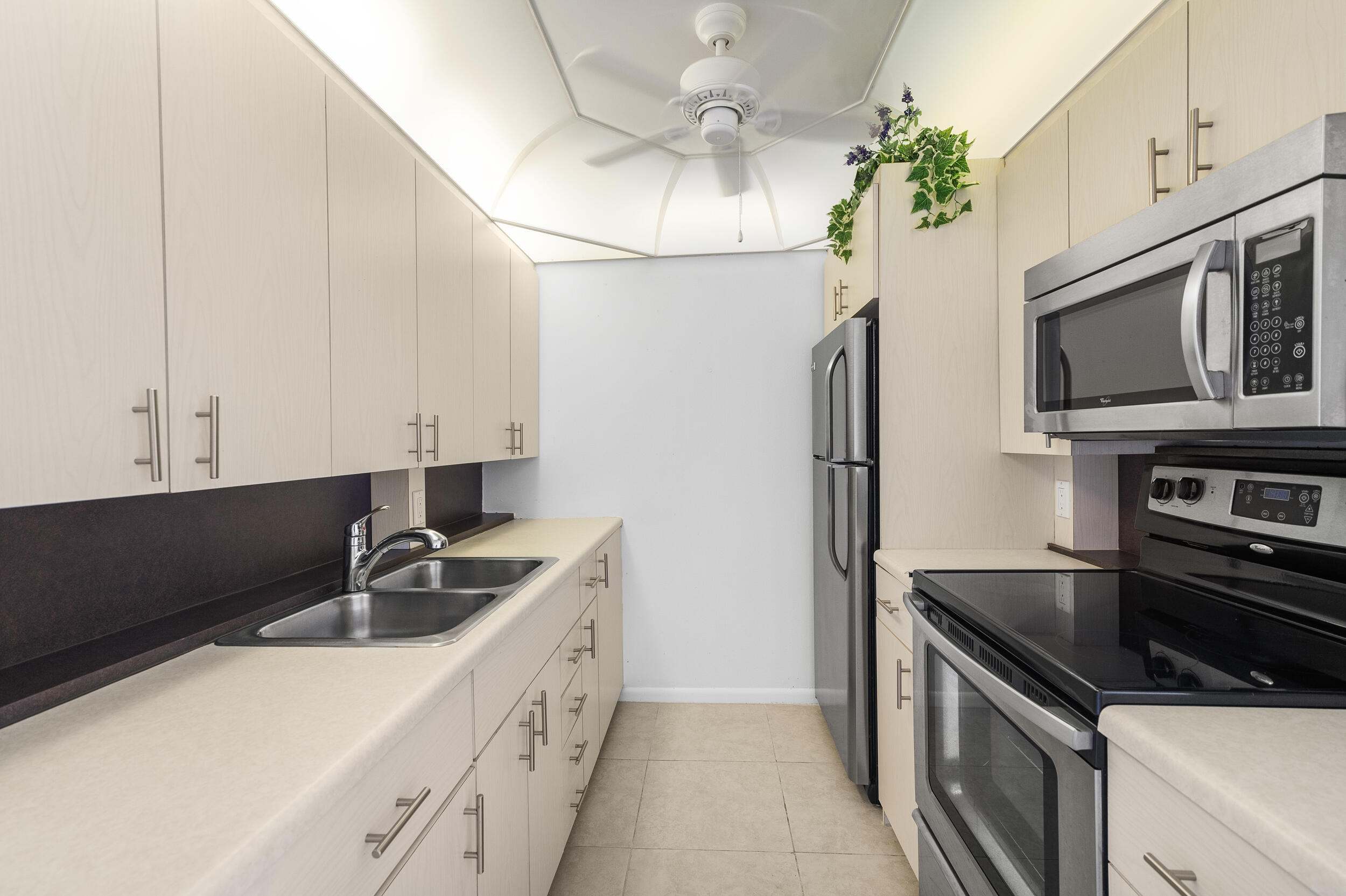3089 Cornwall East, Unit E Boca Raton, FL 33434 - Photo 13 of 39 a kitchen with stainless steel appliances granite countertop a sink stove and refrigerator