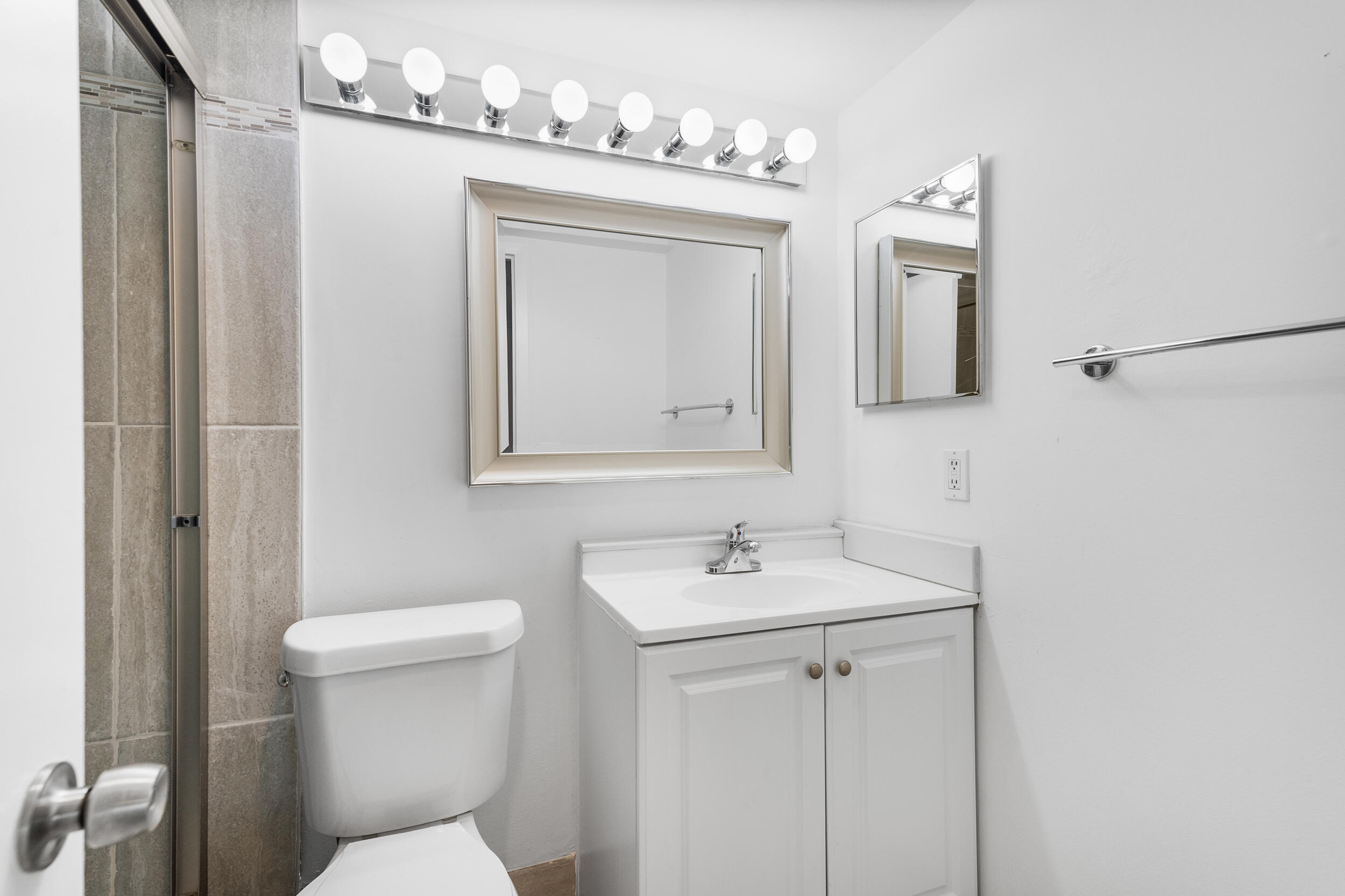 3089 Cornwall East, Unit E Boca Raton, FL 33434 - Photo 23 of 39 a bathroom with a toilet a sink and mirror