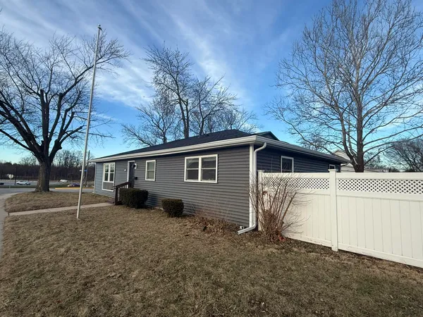 a view of a small white house next to a yard