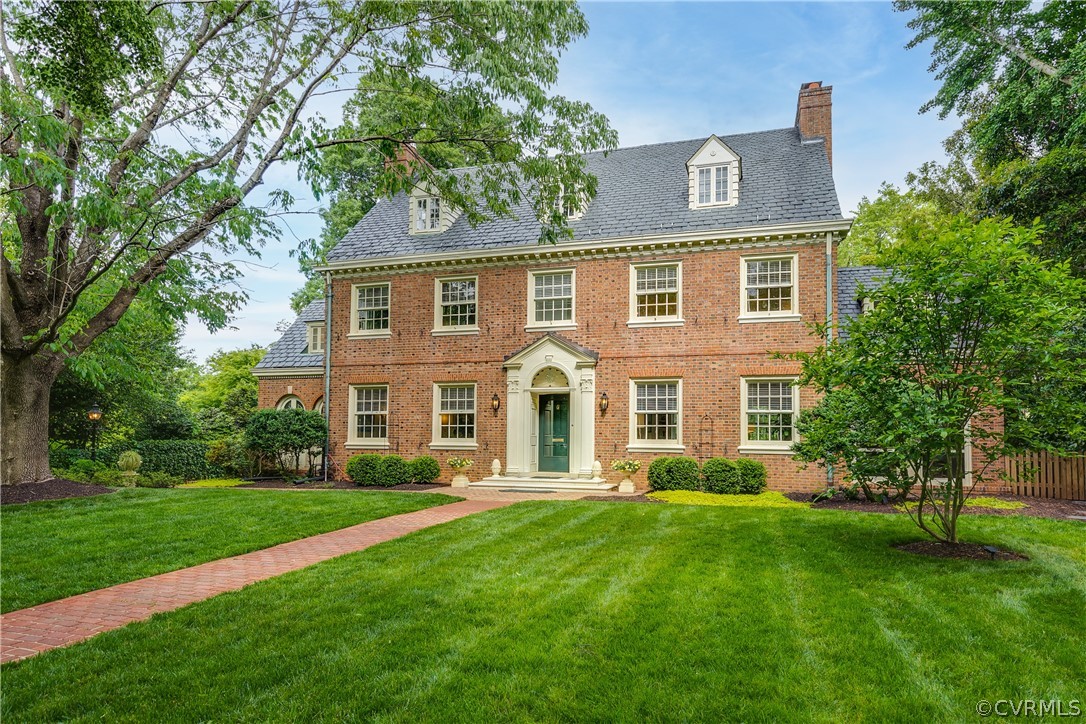 a front view of a house with a garden and trees