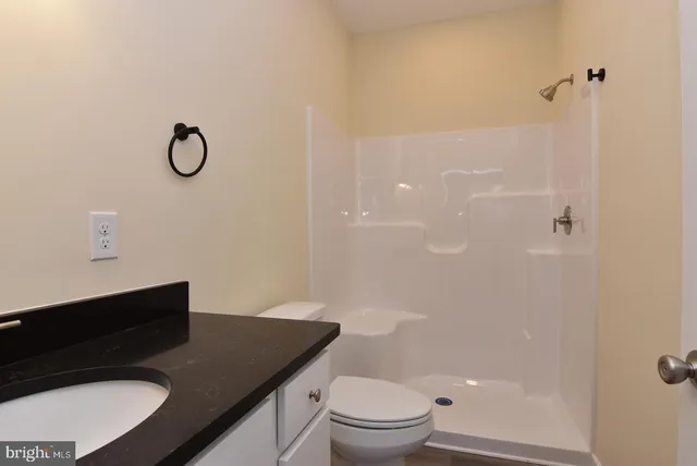 a bathroom with a granite countertop sink toilet a mirror and shower