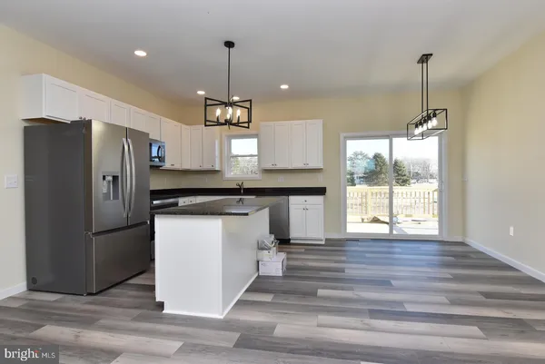 a kitchen with stainless steel appliances granite countertop a refrigerator a sink dishwasher a stove and a wooden floor