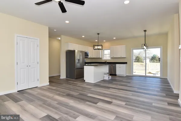 a view of a kitchen with a refrigerator wooden floor and a ceiling fan