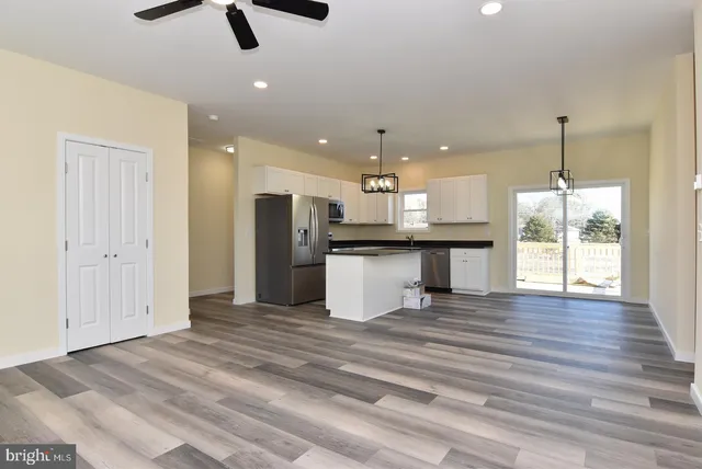 a view of a kitchen with a refrigerator wooden floor and a ceiling fan
