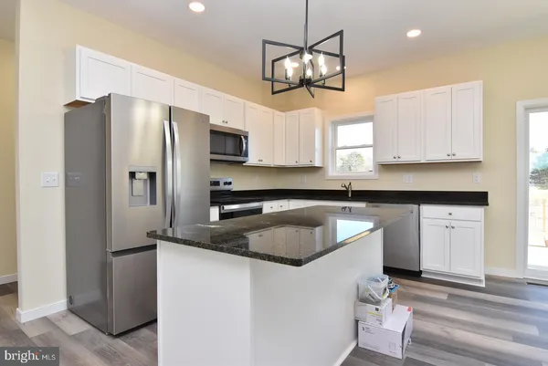 a kitchen with stainless steel appliances granite countertop a sink refrigerator and microwave
