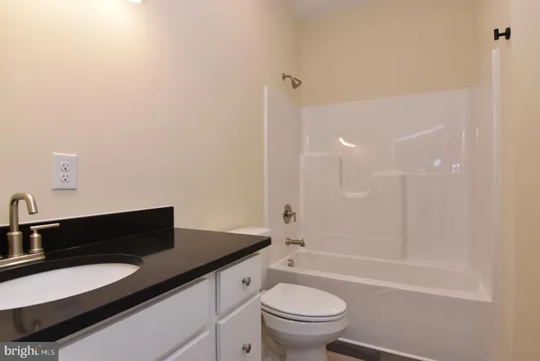 a bathroom with a granite countertop sink a toilet a mirror and bathtub