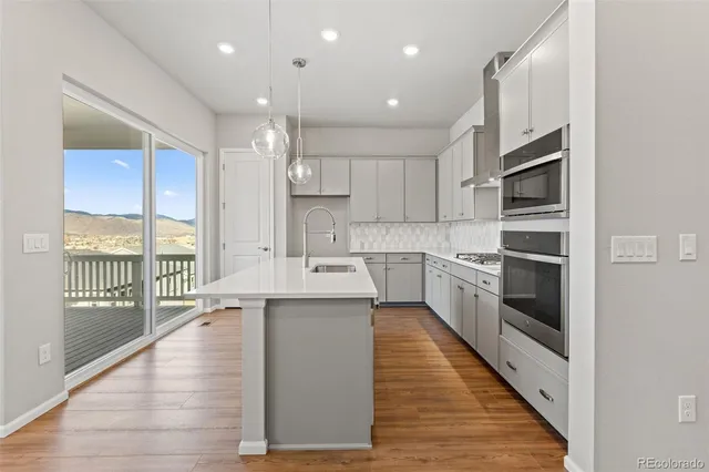 a kitchen with a sink stainless steel appliances and wooden floor