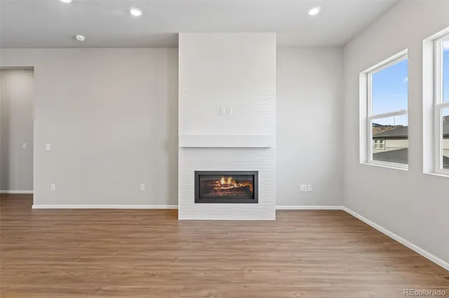 an empty room with wooden floor a fireplace and a window