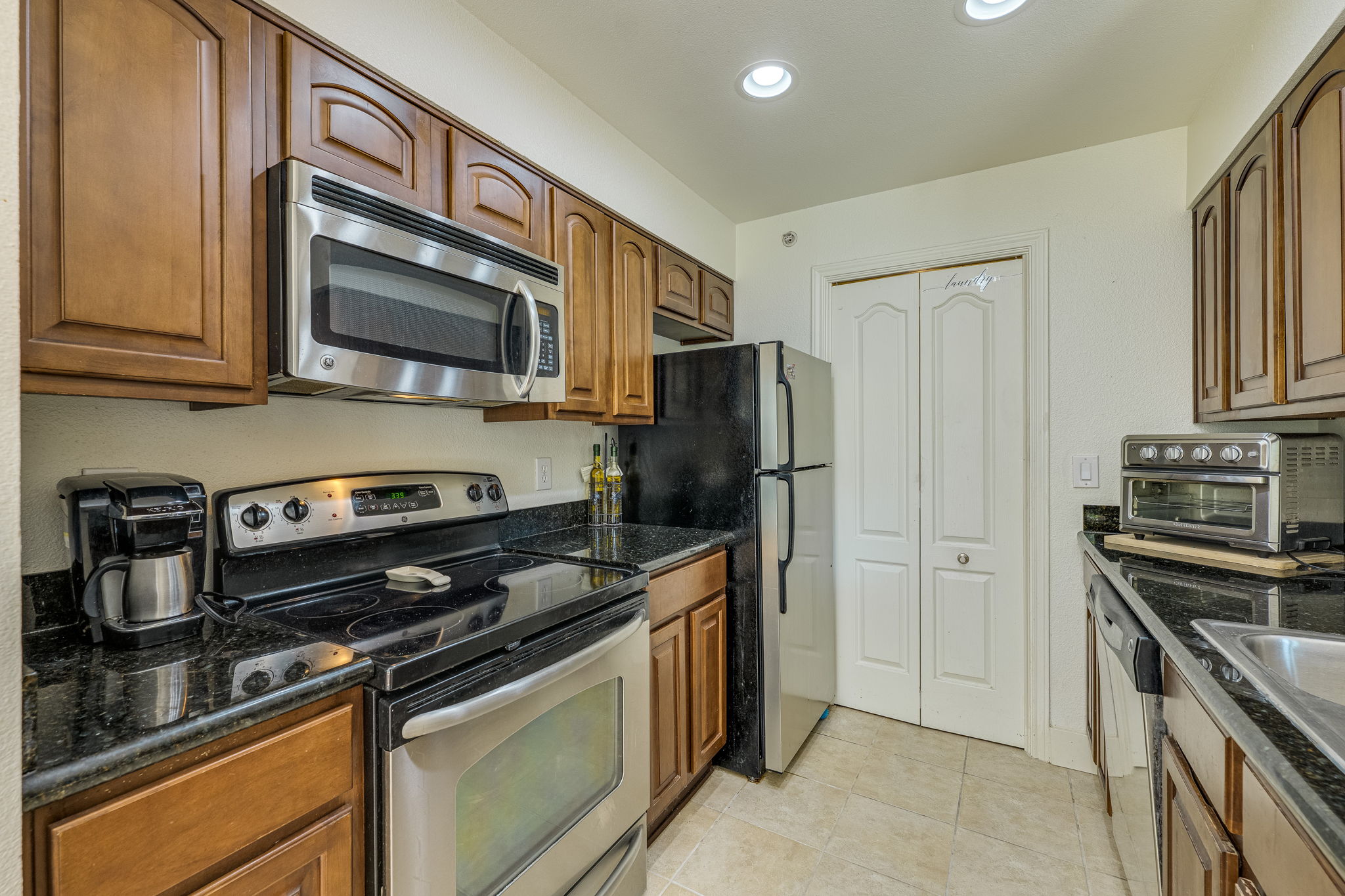 6000 Shepherd Mountain Cove, Unit 807 Austin, TX 78730 - Photo 12 of 38 Kitchen with stainless steel appliances, recessed lighting, granite countertops and brown cabinets.
