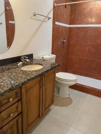 a bathroom with a granite countertop toilet sink and mirror