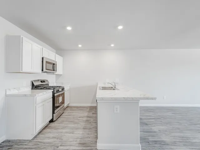 a kitchen with stainless steel appliances granite countertop a sink stove and refrigerator