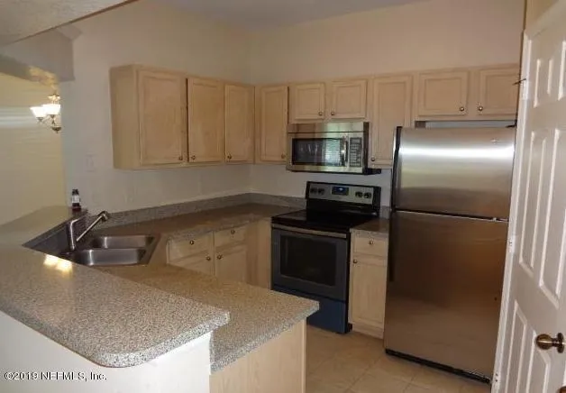 a kitchen with stainless steel appliances granite countertop a sink a refrigerator and a granite counter tops