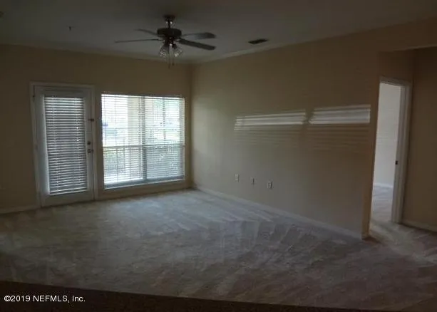 an empty room with windows and fan