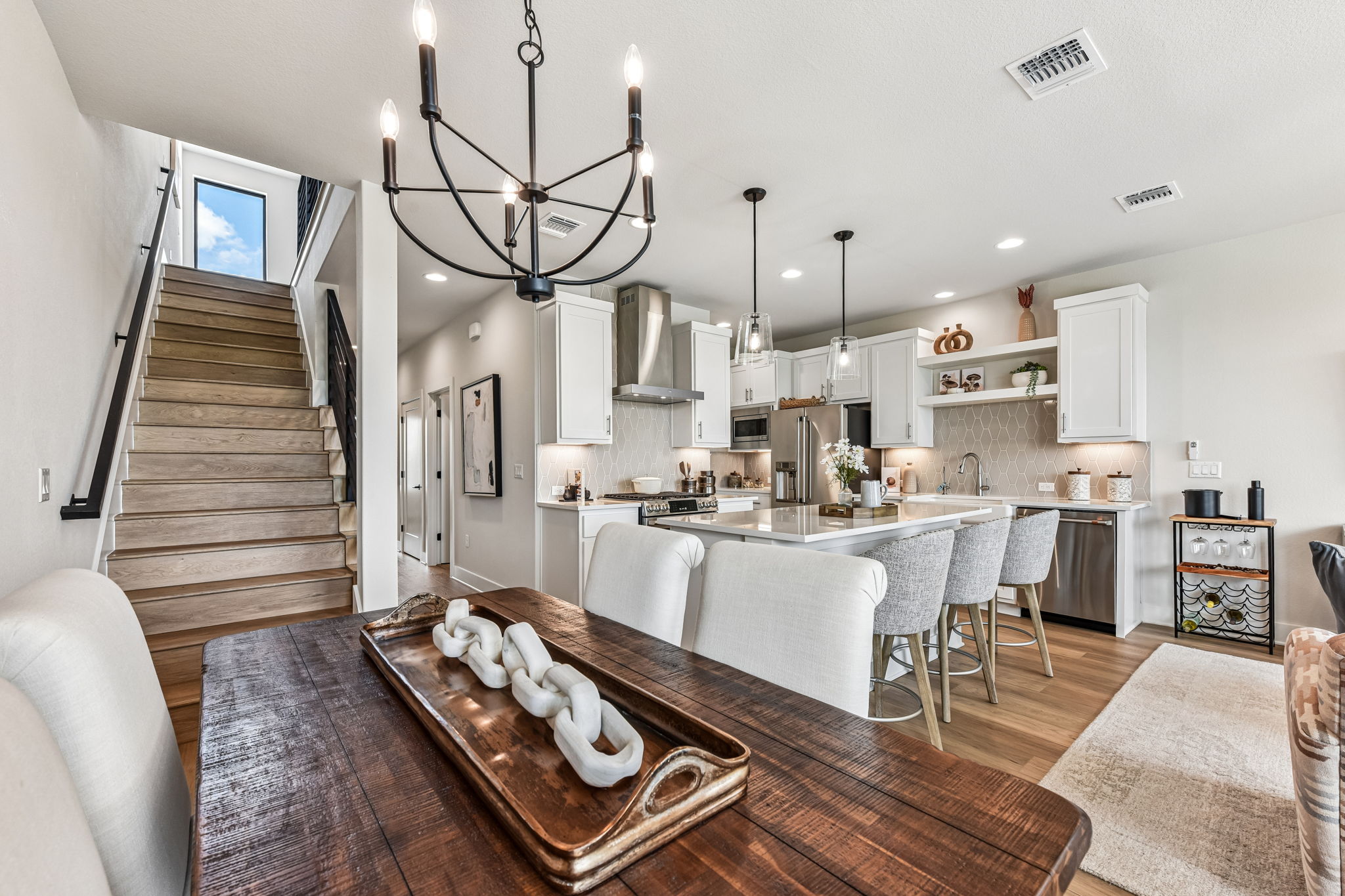 9033 Cattle Baron Path Austin, TX 78747 - Photo 10 of 40 Culinary excellence awaits in this well-appointed kitchen, flowing into an inviting dining space and leading to a sleek wooden staircase.