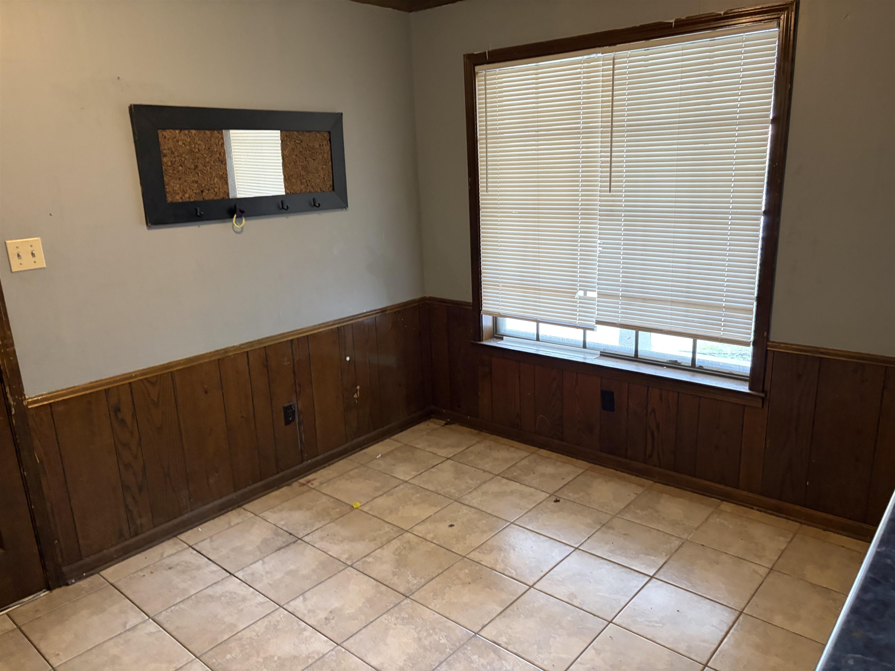 4993 Cedar View Road Memphis, TN 38118 - Photo 21 of 23 Room featuring light-toned square floor tiles, wood paneling, and a single window with horizontal blinds