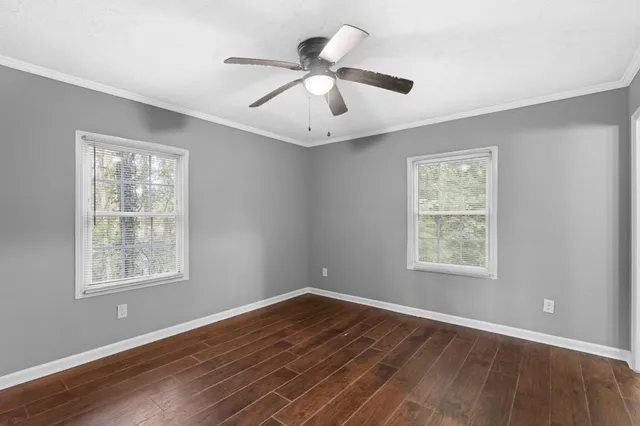 a view of an empty room with wooden floor and a window