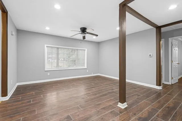 a view of an empty room with wooden floor and a window