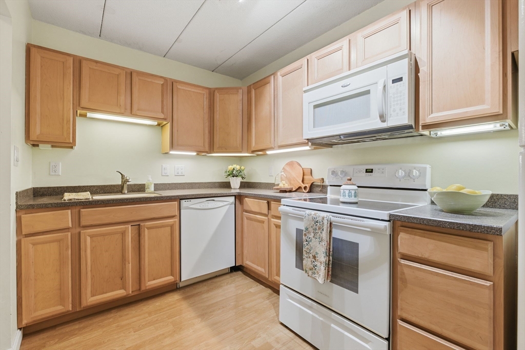 50 Water Street, Unit 46 Medford, MA 02155 - Photo 5 of 37 a kitchen with stainless steel appliances granite countertop a sink and cabinets with wooden floor