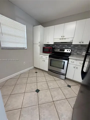 a kitchen with granite countertop a stove a sink and a white cabinets