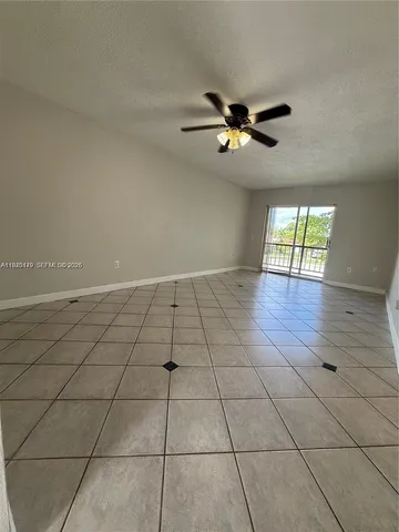 an empty room with windows and ceiling fan