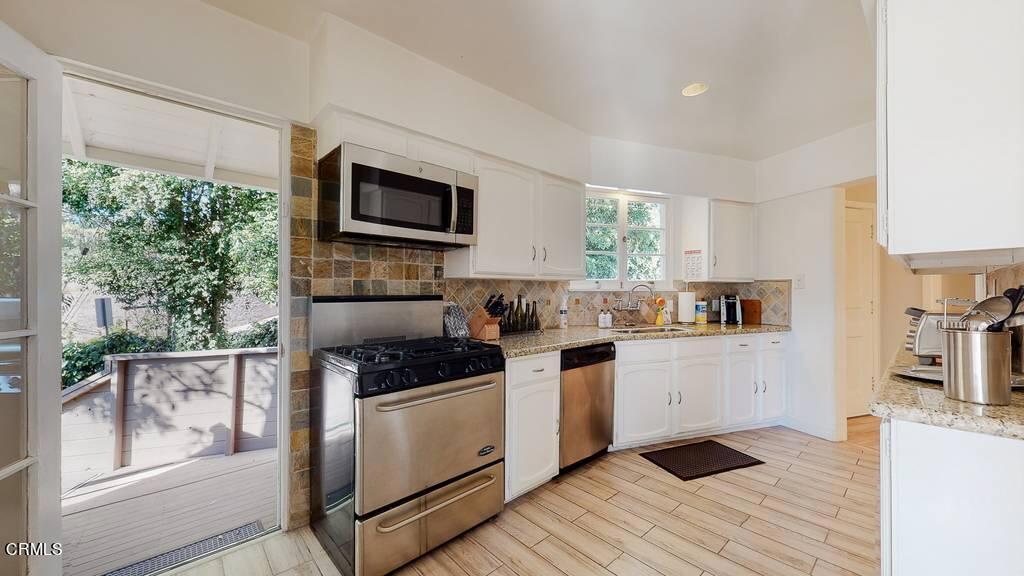 101 South Rockingham Avenue Los Angeles, CA 90049 - Photo 15 of 44 a kitchen with stainless steel appliances kitchen island granite countertop a stove a sink and a refrigerator