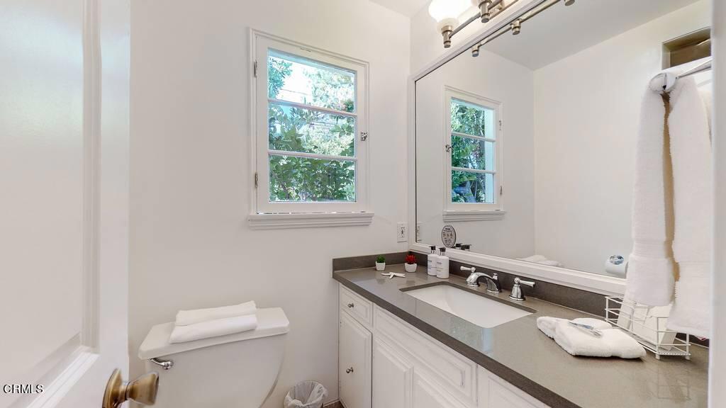 101 South Rockingham Avenue Los Angeles, CA 90049 - Photo 30 of 44 a bathroom with a granite countertop sink toilet and mirror
