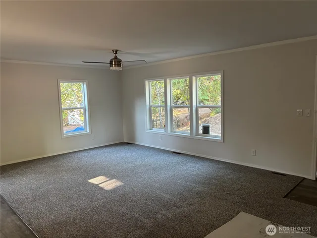 an empty room with windows and ceiling fan