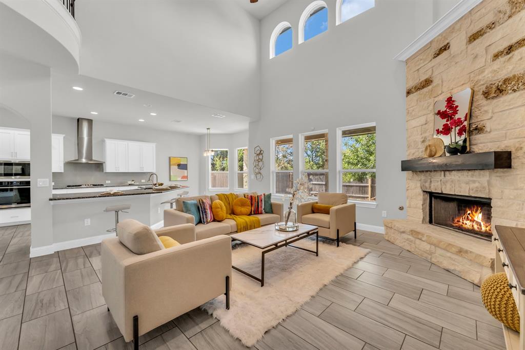 110 Magona Trail Georgetown, TX 78628 - Photo 16 of 38 A spacious living area flows into a chef's kitchen, featuring soaring ceilings and a cozy fireplace.
