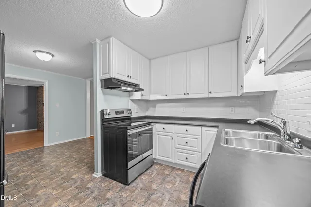 a kitchen with granite countertop a sink stove and cabinets