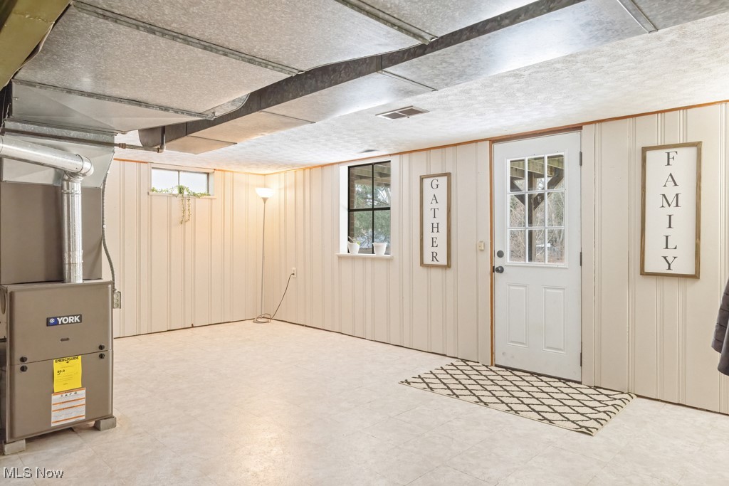 4551 17th Street Northwest Canton, OH 44708 - Photo 31 of 39 Below grade area featuring wood walls, heating unit, visible vents, and tile patterned floors