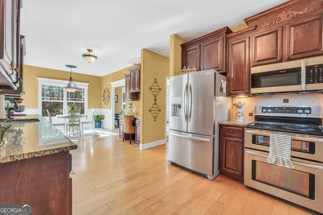 a kitchen with granite countertop a refrigerator stove top oven and sink