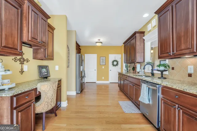 a large kitchen with stainless steel appliances granite countertop a refrigerator a sink dishwasher a stove and a dining table with wooden floor