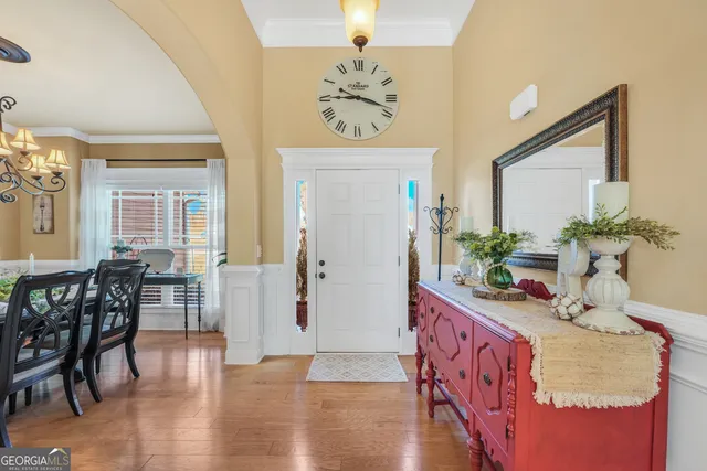 a dining room with wooden floor a chandelier a wooden table and chairs