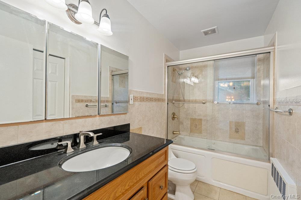 15 Morris Drive Syosset, NY 11791 - Photo 24 of 32 a bathroom with a granite countertop sink toilet a mirror a bathtub and shower