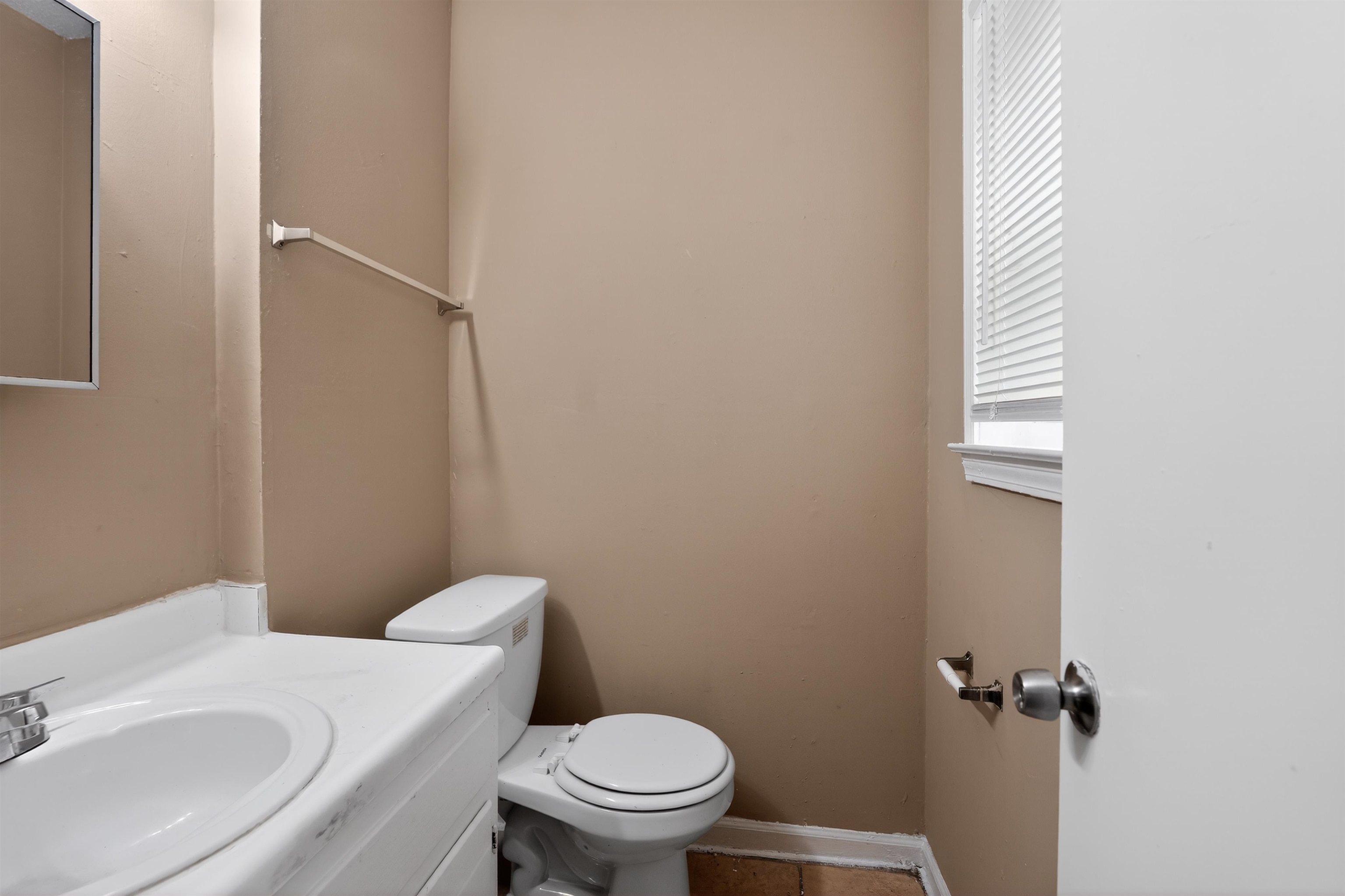 3608 Cane Ridge Drive Memphis, TN 38109 - Photo 28 of 31 Bathroom featuring a white vanity with integrated sink, chrome faucet, white toilet, and window with blinds