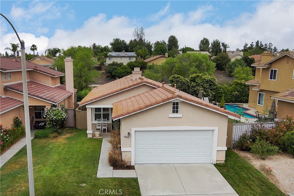 a view of a white house next to a yard with potted plants