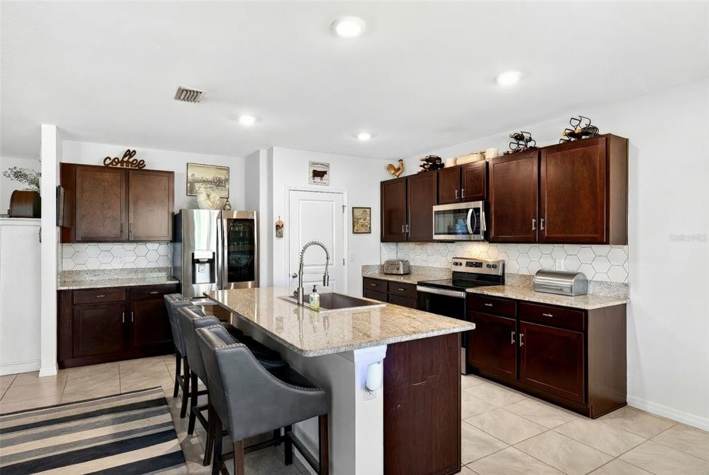 508 Hickory Course Loop Ocala, FL 34472 - Photo 30 of 40 a kitchen with stainless steel appliances granite countertop a sink dishwasher a stove and a refrigerator with wooden floor