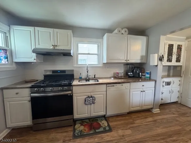 a kitchen with cabinets appliances and a wooden floor