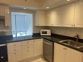a kitchen with granite countertop white cabinets and a sink