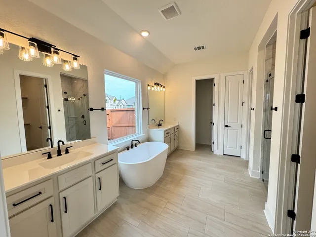a spacious bathroom with a tub shower and mirror
