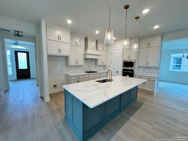 a kitchen with kitchen island a sink a stove a center island and wooden floor