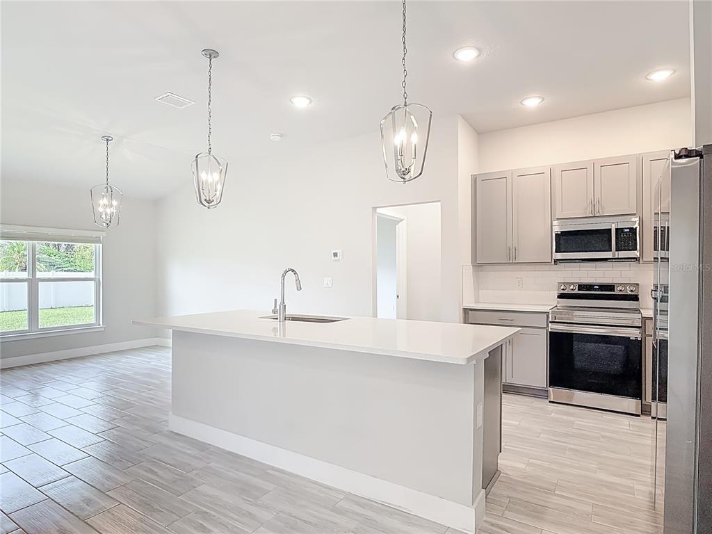 60 Ballenger Lane Palm Coast, FL 32137 - Photo 12 of 60 a kitchen with stainless steel appliances a stove a sink and white cabinets with wooden floor