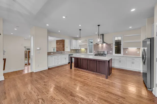 a large kitchen with granite countertop a large counter top a sink stainless steel appliances and cabinets