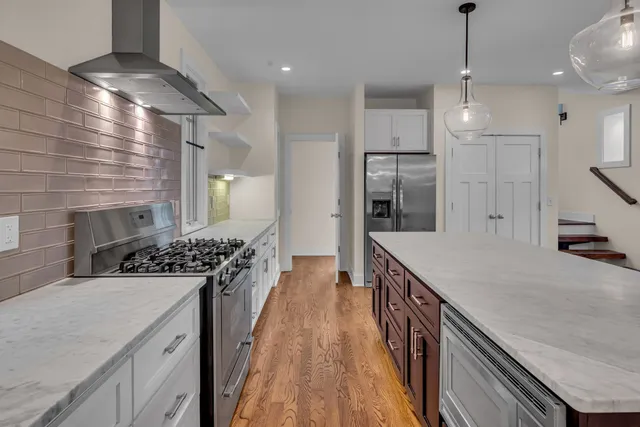a kitchen with stainless steel appliances granite countertop a sink a stove and a wooden floors