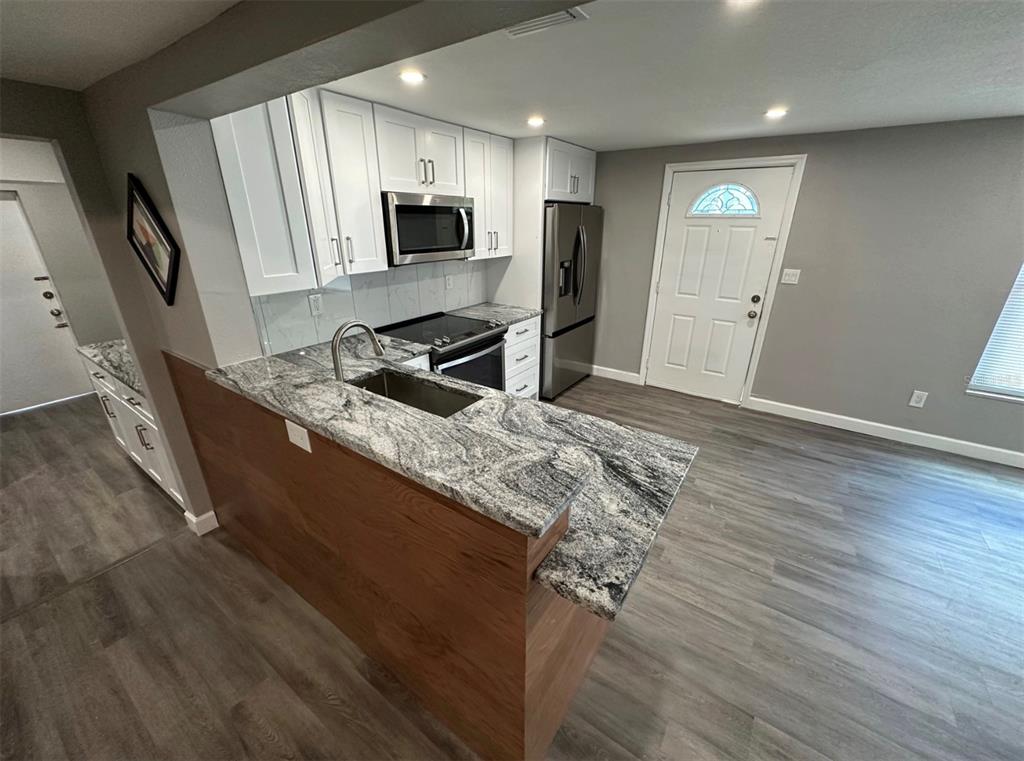 2301 Trelain Drive South St. Petersburg, FL 33712 - Photo 5 of 16 a kitchen with granite countertop a sink a stove top oven a refrigerator and white cabinets