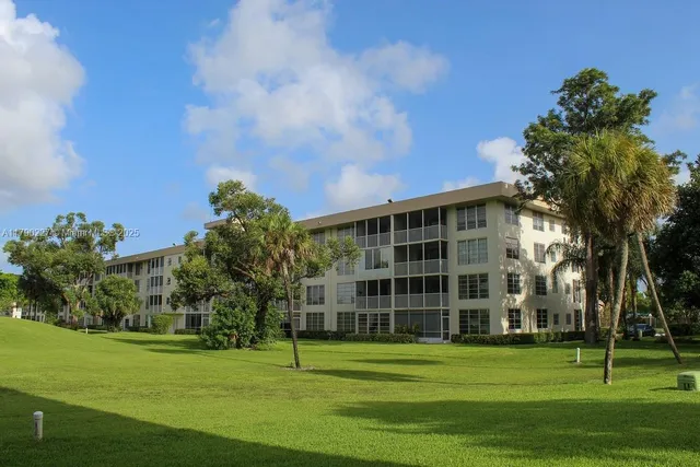 a view of a tall building in a big yard with large trees