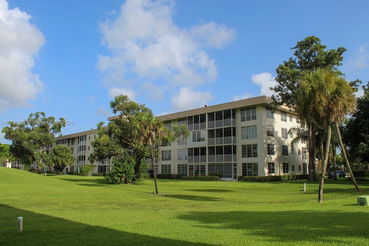 2900 North Palm Aire Drive, Unit 108 Pompano Beach, FL 33069 - Photo 5 of 17 a view of a tall building in a big yard with large trees